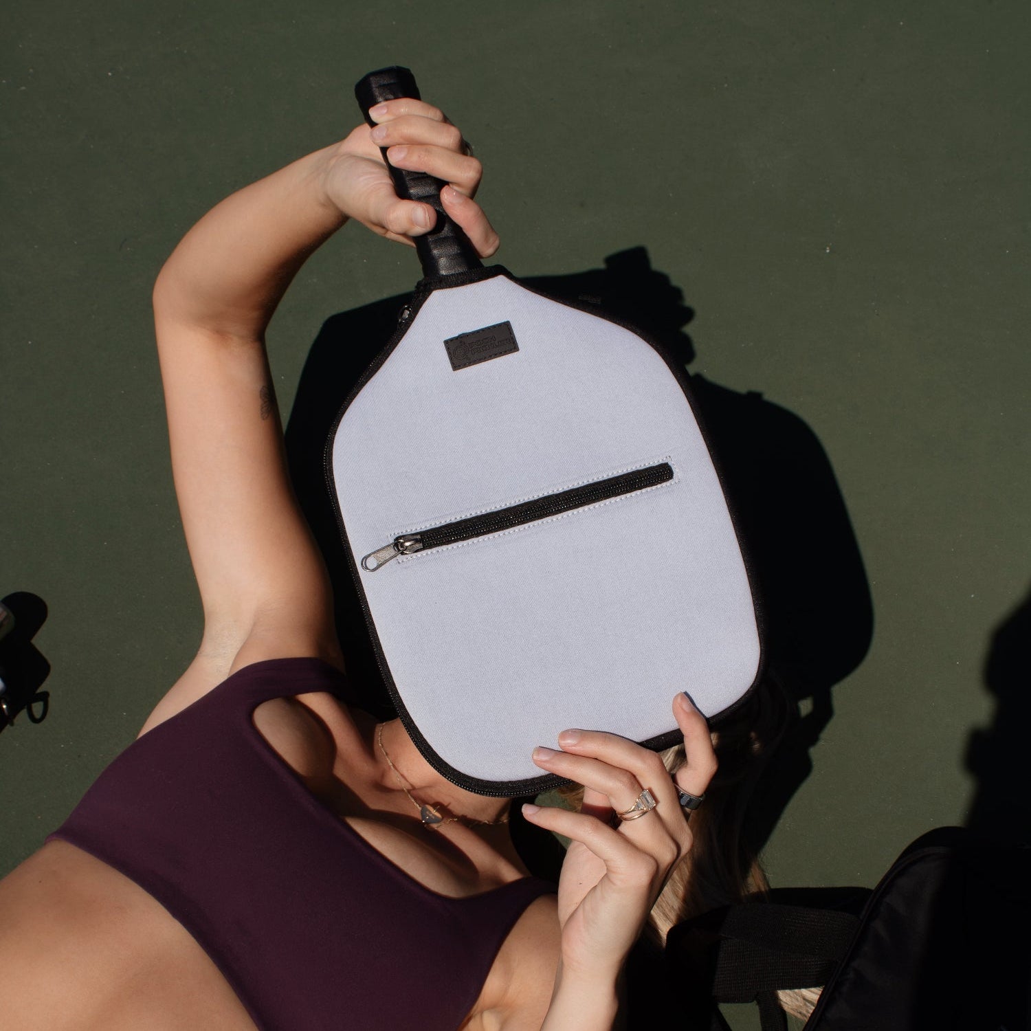 Person holding a black and white Pickleball Paddle on a court